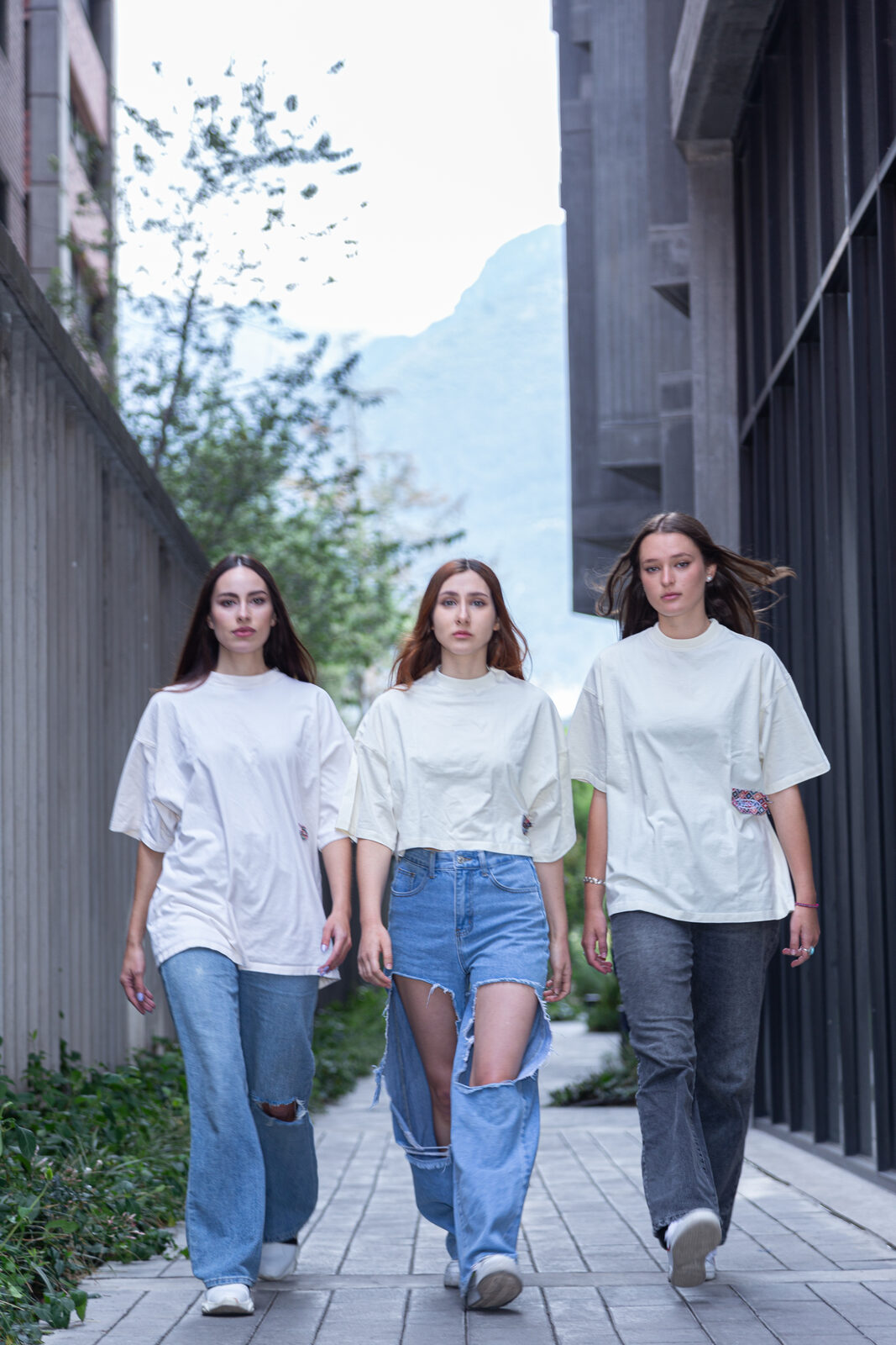 Three models in oversized BLEACH tees against mountains